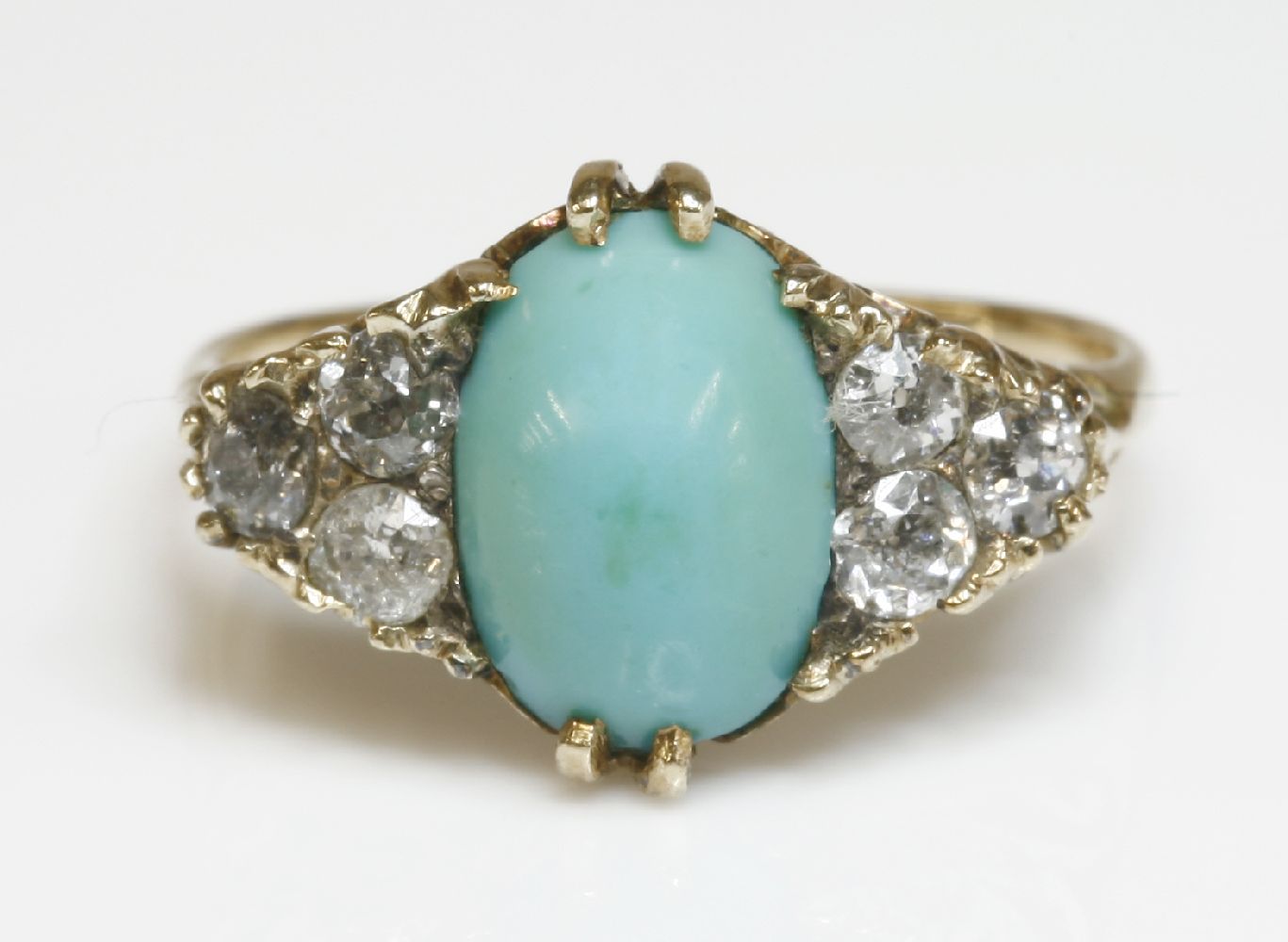 A late Victorian turquoise and diamond carved head ring,with an oval cabochon turquoise, claw set to