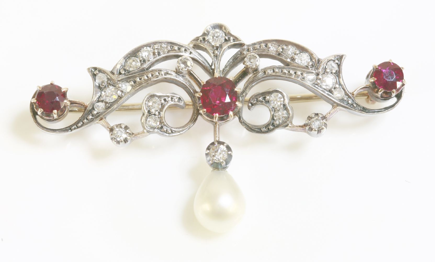 A late Victorian, ruby, diamond and pearl brooch/pendant, c.1890, a scrolling foliate bar, grain set