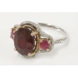 A ruby and diamond ring, with a central oval mixed cut ruby, glass filled, a small ruby to each