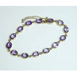 A 9ct gold amethyst bracelet, with a line of rub set oval mixed cut amethysts