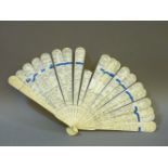 A Canton ivory brisé fan, circa 1860, carved with numerous figures, pavillions and trees around a