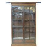 A mahogany glazed bookcase, the plain and dentil cornice over glazed full length doors, with four