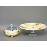 Two Clarice Cliff relief moulded items, sugar bowl and chrome lid, and a cake stand