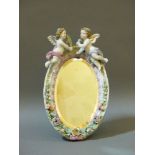 A large 19th century Meissen style mirror, surmounted with cherubs and with floral encrustations,