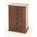 A miniature Wellington chest of six drawers, each containing a collection of curios and souvenirs,