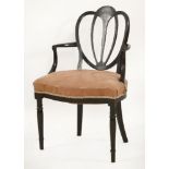 An Edwardian ebonised elbow chair, with a shaped back