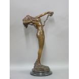 A reproduction bronze of an Art Nouveau style nude figure holding a garland of fruit