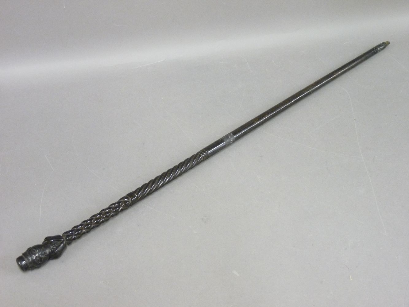 An antique tribal walking stick, with a figural head teminal handle, with geometric and spiral twist