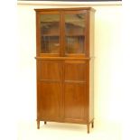 An Edwardian glazed bookcase over cupboard, enclosing shelves, 102cm wide, 214cm high, 44cm deep