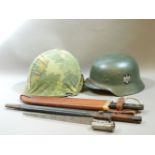 A German WWII steel helmet, a US helmet, two bayonets, and a machete in a leather scabbard