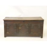 A late 17th/early 18th century oak coffer, with a carved panelled front, 135cm wide, 61cm deep, 63cm