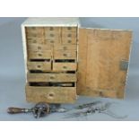 A wooden watch maker's cabinet of small drawers, with tools, spares, glasses, etc, three metal