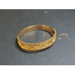 A 9ct gold repoussé hinged bangle, with milled wire decorative edge, Birmingham 1916