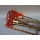 Three leather hunting whips, two fly whisks, and two further items