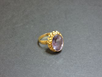 A Continental synthetic colour change sapphire gold ring, with a flower head border, tested as