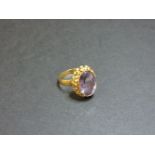 A Continental synthetic colour change sapphire gold ring, with a flower head border, tested as