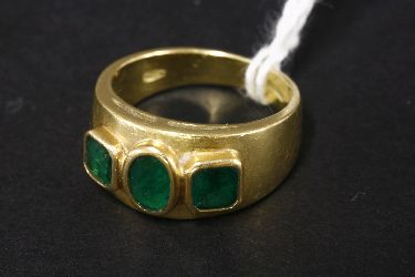 A three stone emerald tapered gold band ring, marked 750