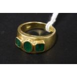 A three stone emerald tapered gold band ring, marked 750