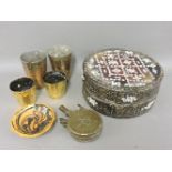 A Middle Eastern brass powder flask, four Islamic brass beakers, a rattan food container with