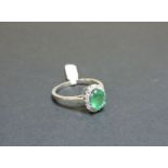 An 18ct white gold emerald and diamond oval cluster ring