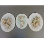 A pair of German biscuit porcelain wall plaques, modelled with applied figures of winged cherubs,