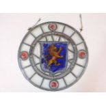 A late 19th century stained glass roundel, centred with a lion rampant within a blue shield, 35cm