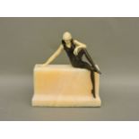 An Art Deco style bronze and ivorine figure of a seated lady, on a marble base