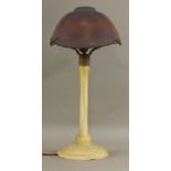 An Art Nouveau coloured glass table lamp,the purple glass shade etched with flying bats, raised on a