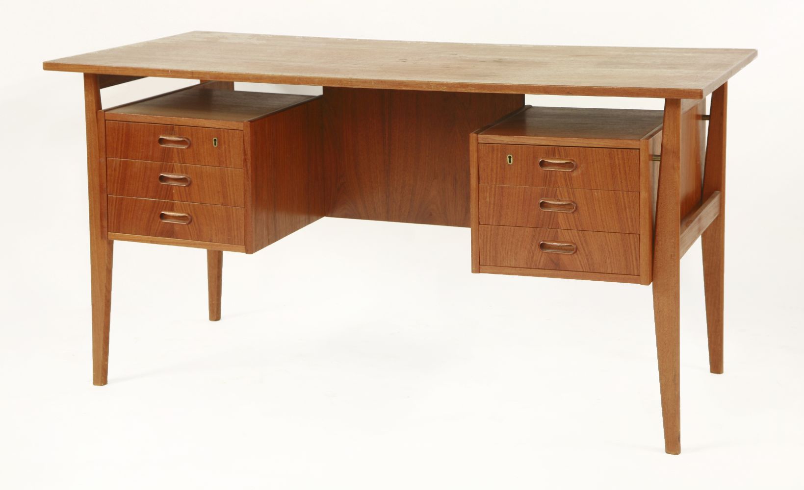 A Danish teak desk,the floating top over three drawers either side and a bookshelf to the reverse,