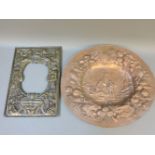 An ornate brass frame, and a Victorian repoussé decorated wall plaque