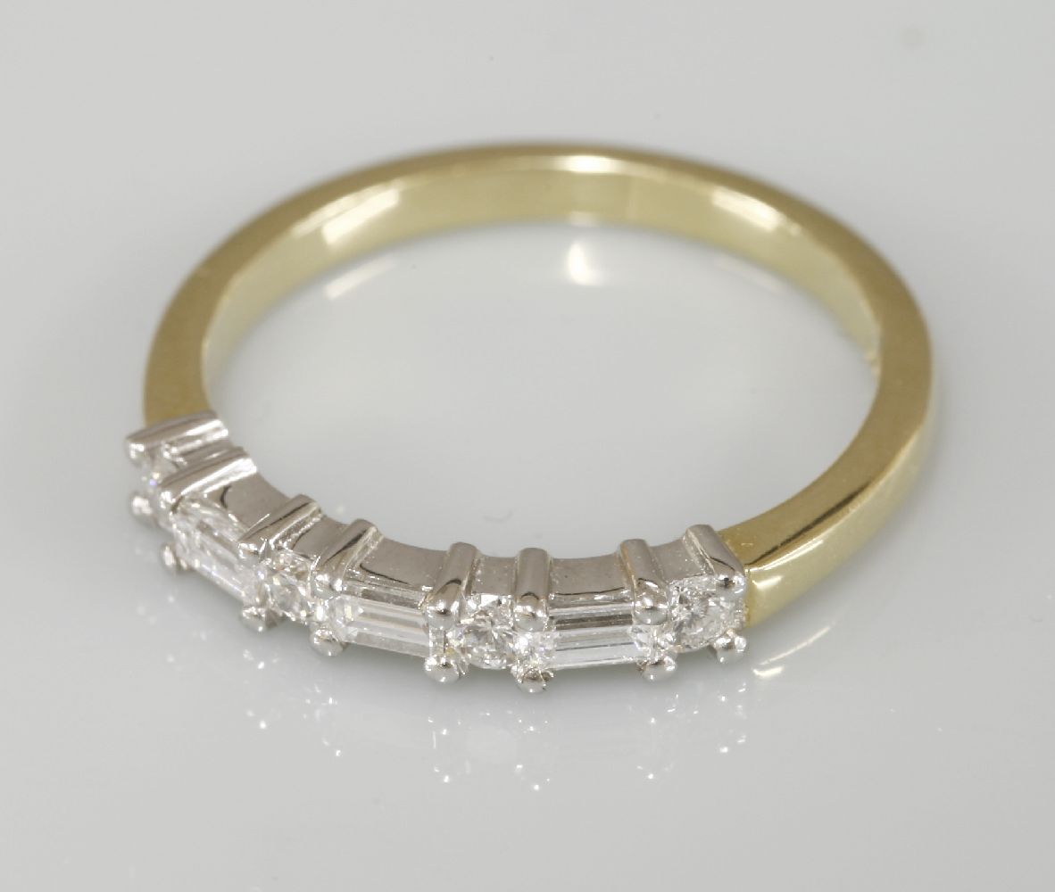 An 18ct yellow and white gold baguette cut diamond and brilliant cut diamond half eternity ring