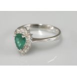 An 18ct white gold pear shaped emerald and diamond cluster ring