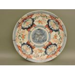 A late 19th century Imari dish, painted in a typical palette with central roundel of leaves within