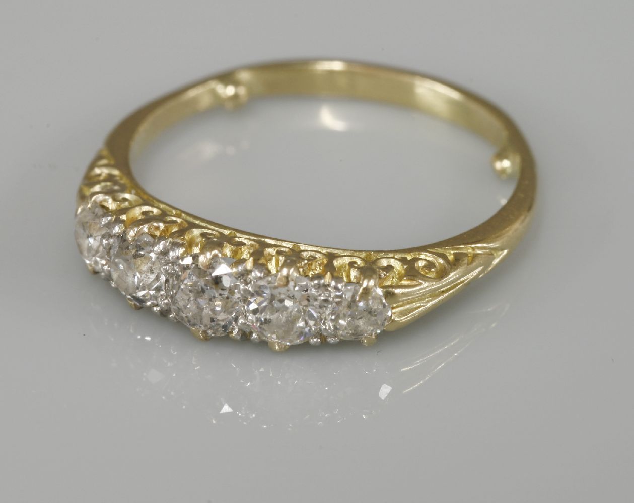 A five stone graduated diamond carved head ring, tested as approximately 18ct gold