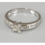 A 9ct white gold four stone princess cut diamond invisibly set ring, with brilliant cut diamond