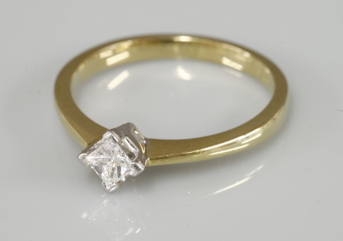 An 18ct gold single stone princess cut diamond ring, claw set in an off set position