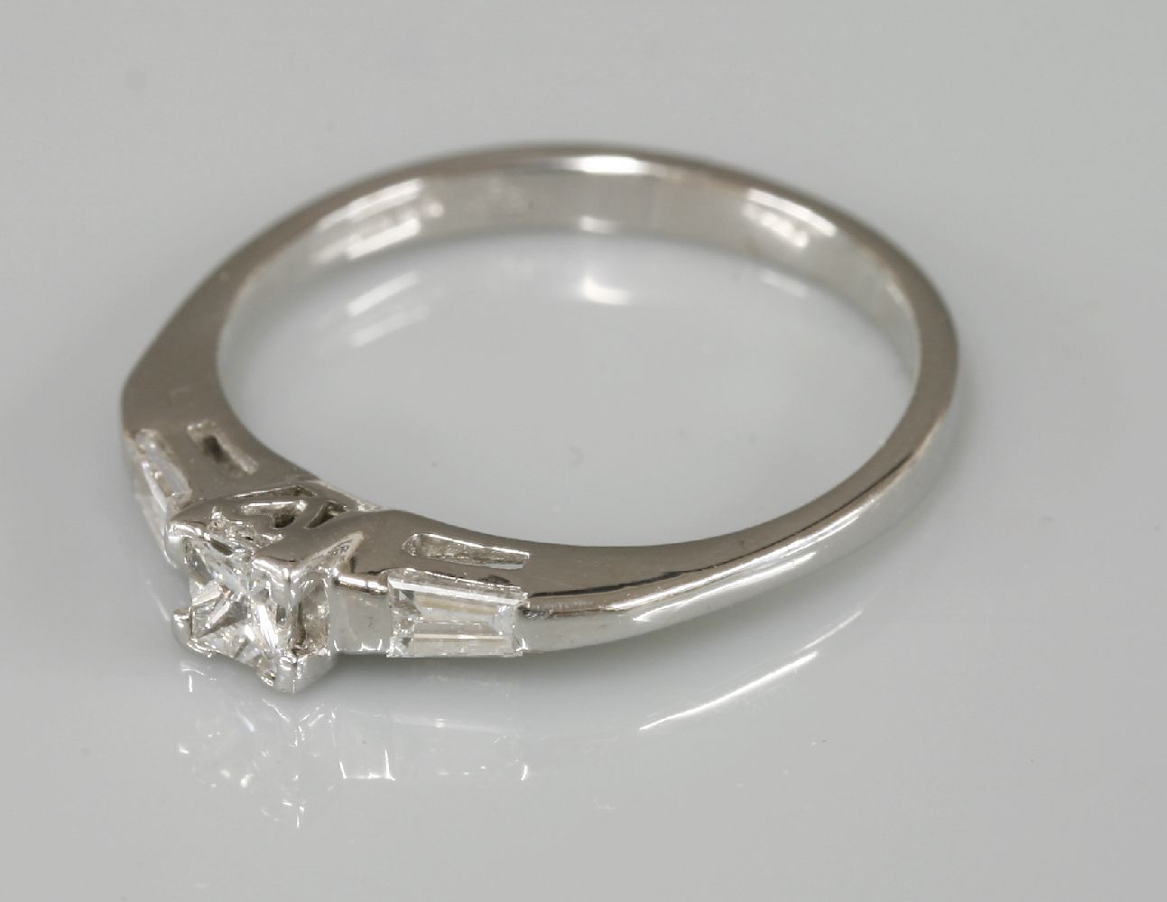 An 18ct white gold single stone princess cut diamond ring, with tapered baguette cut diamond