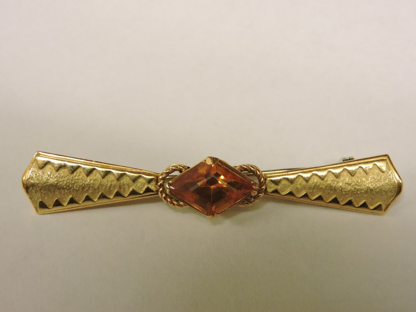 A Continental gold bar brooch, set with a lozenge shaped synthetic sapphire marked 750