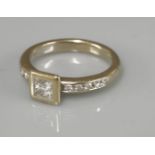 A single stone princess cut diamond ring, with diamond set shoulders, marked 750