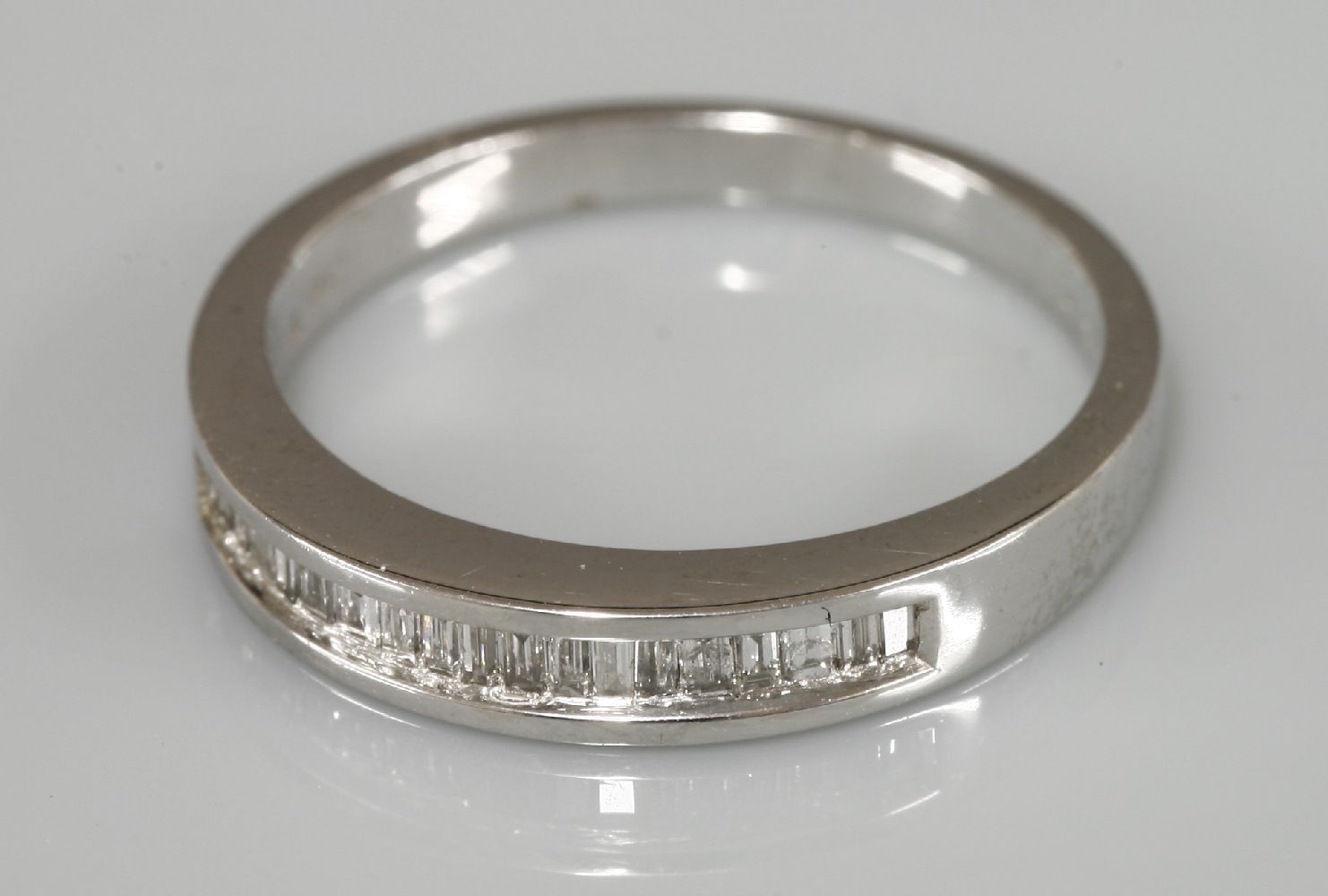 A 9ct white gold baguette cut diamond channel set half eternity ring, 0.25ct stated weight