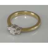 An 18ct gold single stone emerald cut diamond ring, with baguette cut diamond shoulders