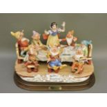 A very large figure group of Walt Disney's Snow White and the Seven Dwarfs, seated at a table, by