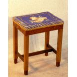 An Art Deco style burr walnut maple and rosewood Stool, the later needlework top depicting shelves