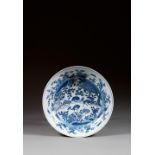 PLAT CREUX en porcelaine et bleu de cobalt sous couverte, monté sur un petit talon, à contour