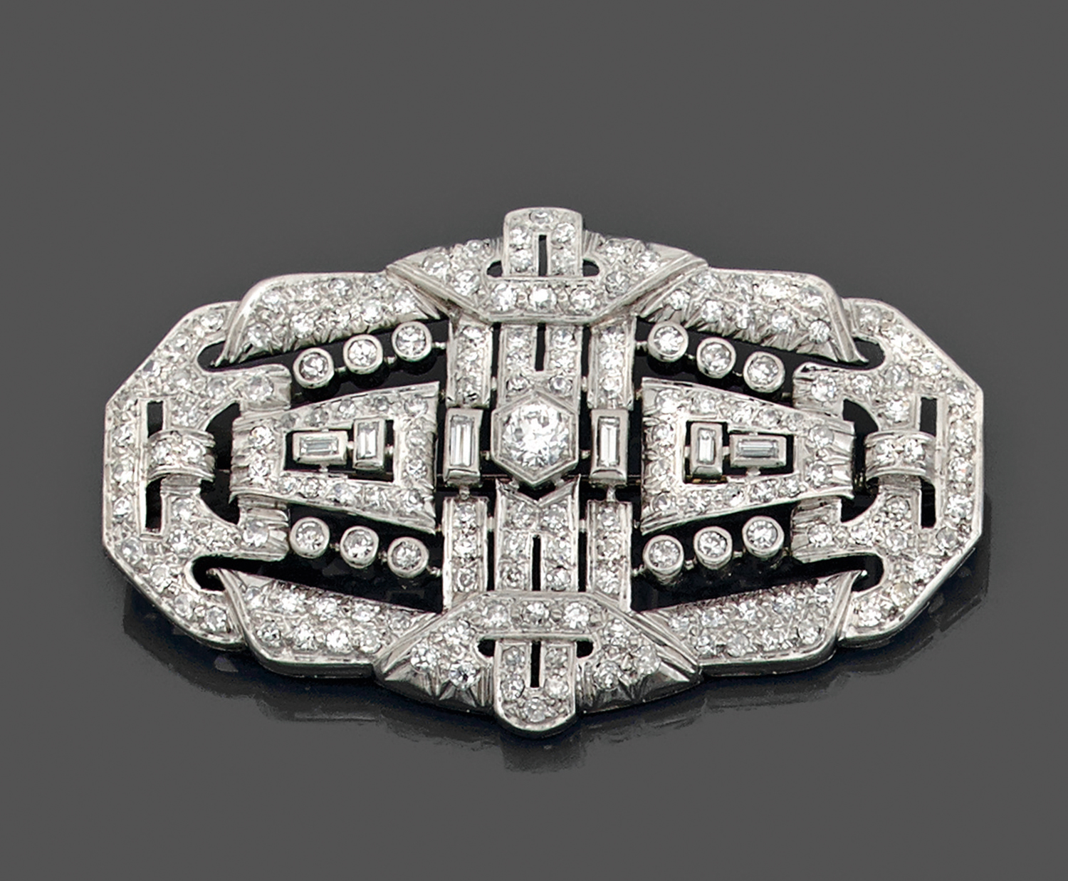 ANNEES 1930GRANDE BROCHE PLAQUEde forme ovale à décor géométrique serti de diamants ronds et