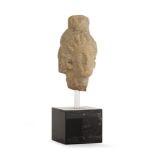 TÊTE En terre cuite provenant d'une statuette votive représentant une jeune femme portant un