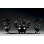 GARNITURE D'AUTEL EN TROIS PIÈCESEn bronze de patine sombre, composée d'un brûle-parfum tripode