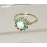 A ladies 9ct gold dress ring, set with a central Cabouchon opal, with a surround of green stones.
