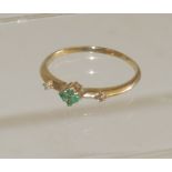 A 9ct gold dress ring, set with four small emeralds to the centre and a small diamond to each
