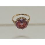 A 9ct gold dress ring, set with a circular, faceted violet, red stone, possibly Fluorite. Ring